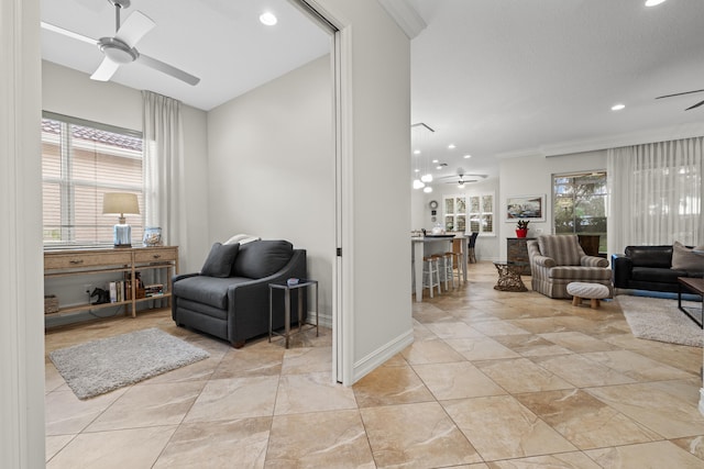 living area featuring crown molding, ceiling fan, and a wealth of natural light