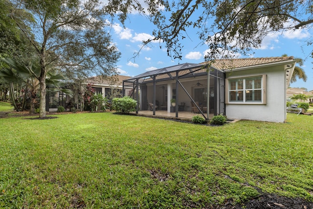 back of property with a yard, a patio area, and glass enclosure