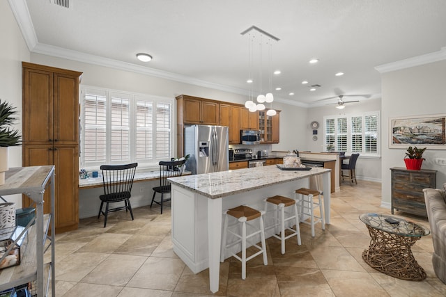 kitchen featuring appliances with stainless steel finishes, a breakfast bar, decorative light fixtures, ornamental molding, and light stone counters