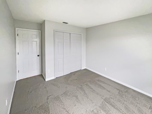 unfurnished bedroom featuring a closet and dark carpet