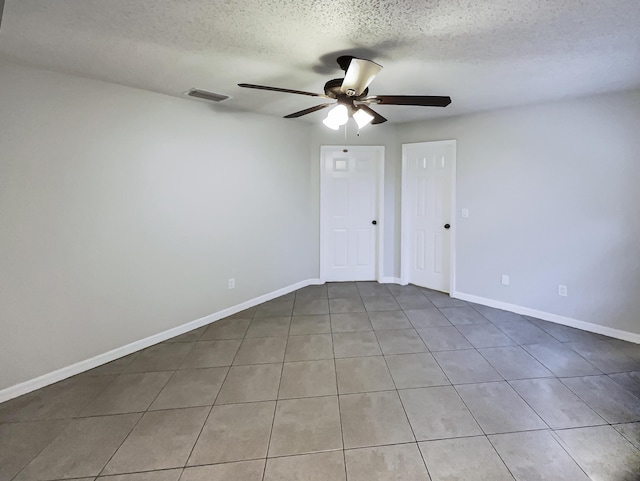 spare room featuring ceiling fan, a textured ceiling, and light tile patterned flooring