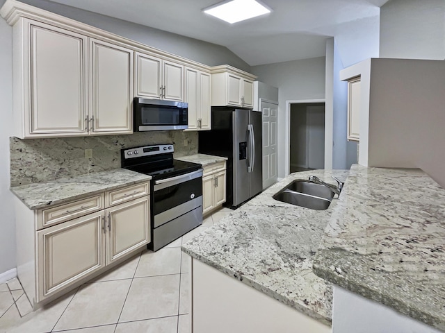 kitchen with vaulted ceiling, sink, light stone counters, decorative backsplash, and stainless steel appliances