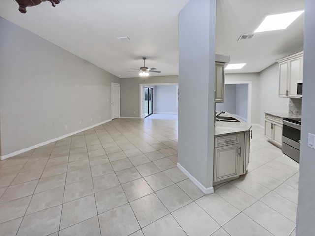 kitchen with ceiling fan, sink, light tile patterned floors, light stone countertops, and stainless steel range with electric cooktop