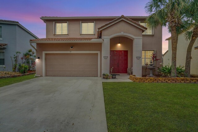 mediterranean / spanish home with a garage and a lawn