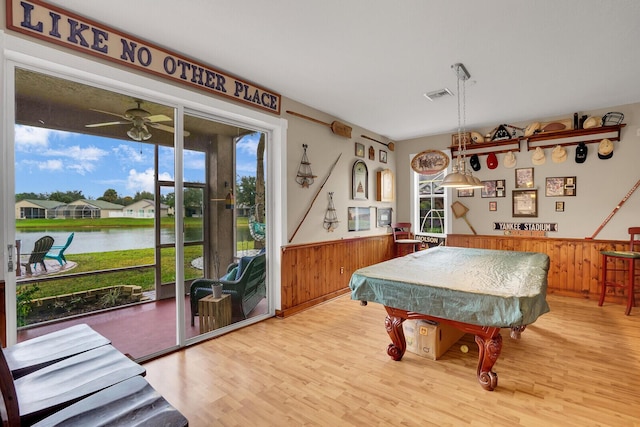 rec room with a water view, pool table, wooden walls, ceiling fan, and hardwood / wood-style floors