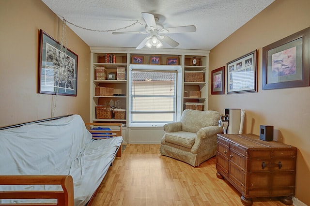 sitting room with ceiling fan, built in features, a textured ceiling, and light hardwood / wood-style flooring