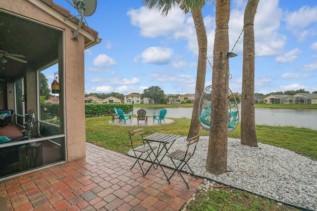 view of patio / terrace with a water view, ceiling fan, and a fire pit