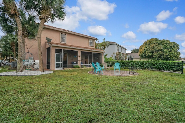 rear view of property with a yard, a patio area, and a sunroom