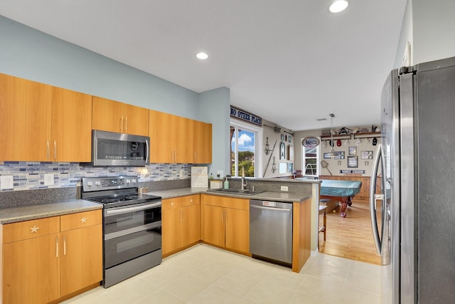 kitchen featuring stainless steel appliances, sink, backsplash, and kitchen peninsula