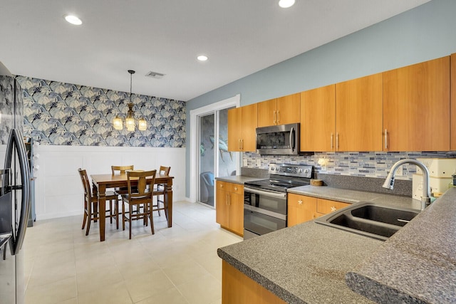 kitchen with appliances with stainless steel finishes, sink, backsplash, hanging light fixtures, and an inviting chandelier