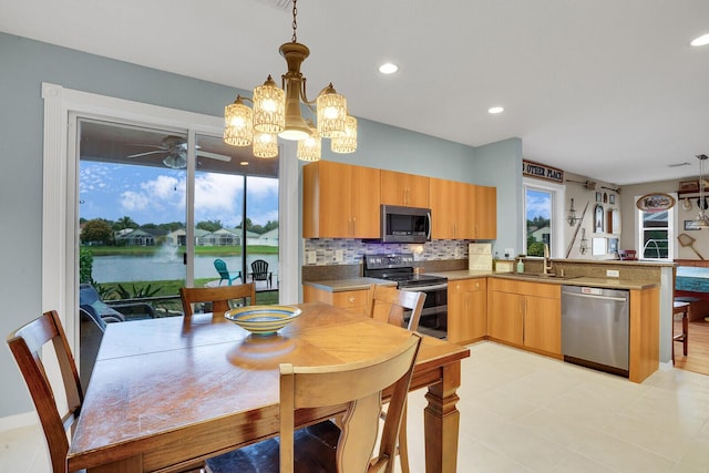 kitchen with pendant lighting, sink, kitchen peninsula, stainless steel appliances, and a water view