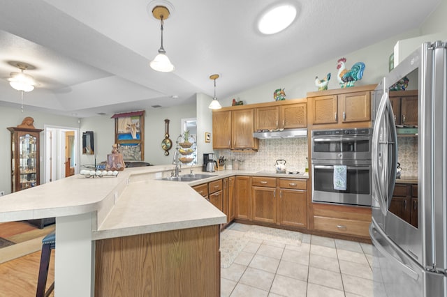 kitchen featuring kitchen peninsula, pendant lighting, backsplash, a kitchen bar, and stainless steel appliances