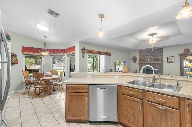 kitchen with a tray ceiling, stainless steel appliances, sink, hanging light fixtures, and light tile patterned floors