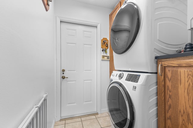 washroom with light tile patterned floors, cabinets, and stacked washer and dryer