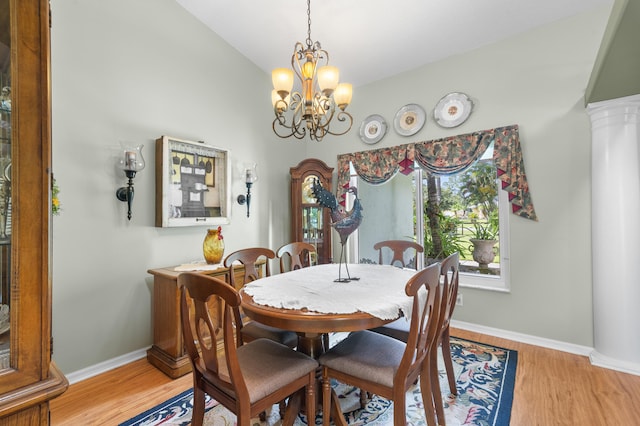 dining room featuring light wood-type flooring, a chandelier, decorative columns, and lofted ceiling