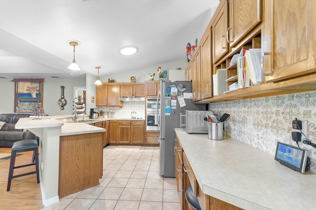 kitchen with kitchen peninsula, decorative light fixtures, backsplash, a breakfast bar area, and lofted ceiling