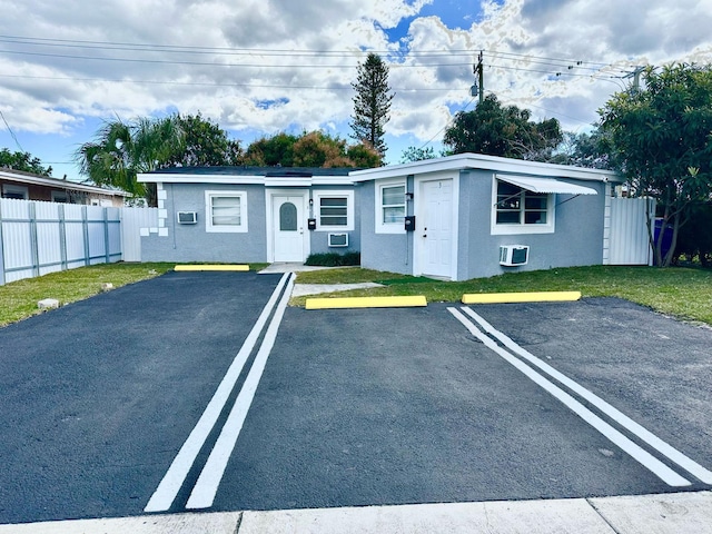 view of front of home with a front lawn and a wall mounted air conditioner