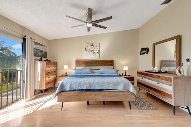 bedroom with ceiling fan, vaulted ceiling, a textured ceiling, and light wood-type flooring