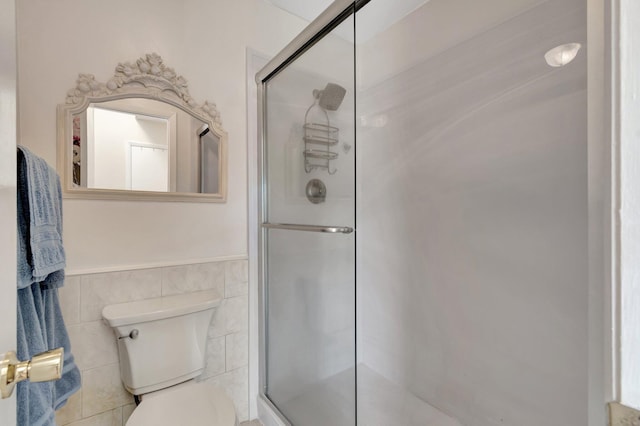 bathroom with tile walls, a shower with shower door, and toilet