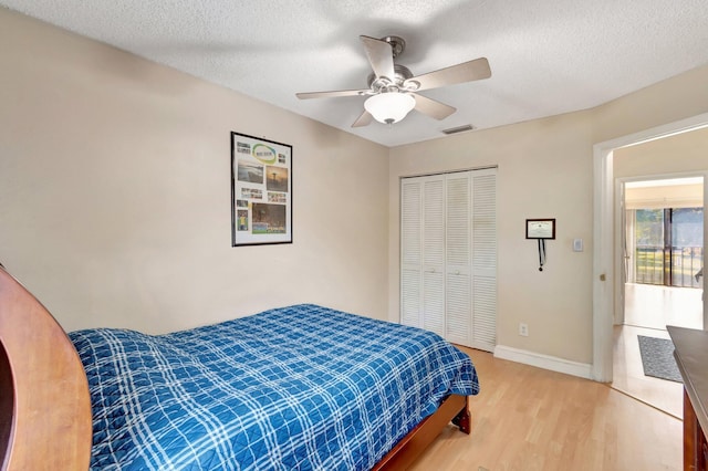 bedroom featuring ceiling fan, a closet, hardwood / wood-style floors, and a textured ceiling