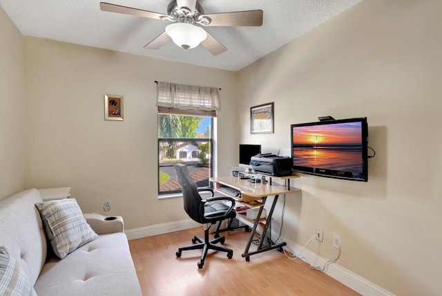 home office with light hardwood / wood-style floors and ceiling fan