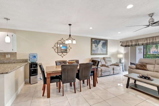 tiled dining room featuring ceiling fan, crown molding, and a textured ceiling