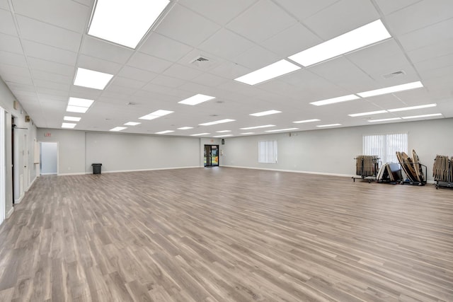 spare room with a paneled ceiling and light wood-type flooring