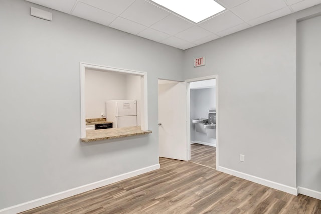 unfurnished room featuring wood-type flooring and a drop ceiling