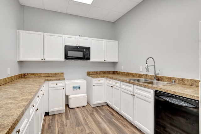 kitchen featuring a paneled ceiling, white cabinetry, sink, light hardwood / wood-style floors, and black appliances