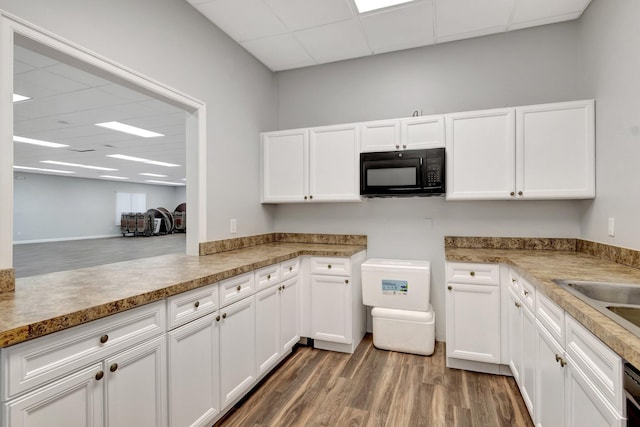 kitchen featuring dark wood-type flooring, a paneled ceiling, kitchen peninsula, and white cabinets