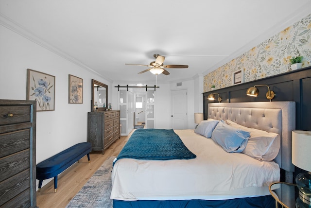 bedroom with ceiling fan, light hardwood / wood-style floors, crown molding, and a barn door