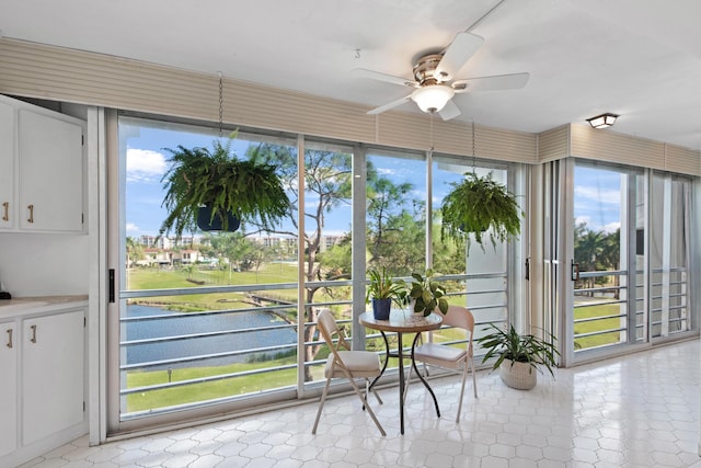 unfurnished sunroom featuring a water view and ceiling fan