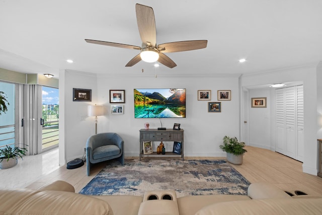 living room with ceiling fan, ornamental molding, and light wood-type flooring