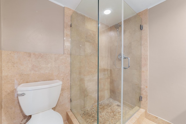 bathroom with an enclosed shower, tile walls, and toilet