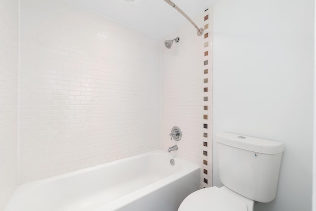 bathroom with tiled shower / bath combo and toilet