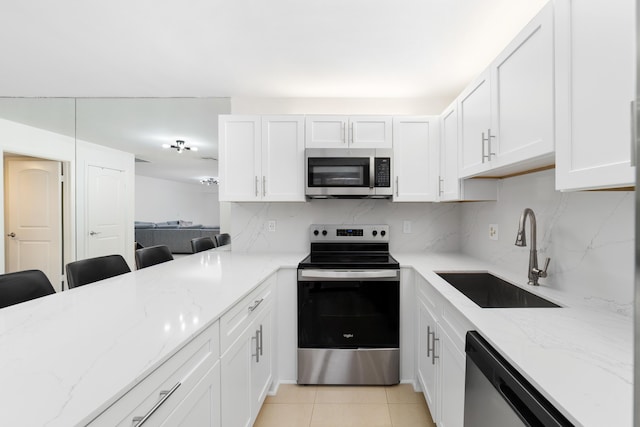 kitchen with white cabinets, stainless steel appliances, tasteful backsplash, sink, and a breakfast bar