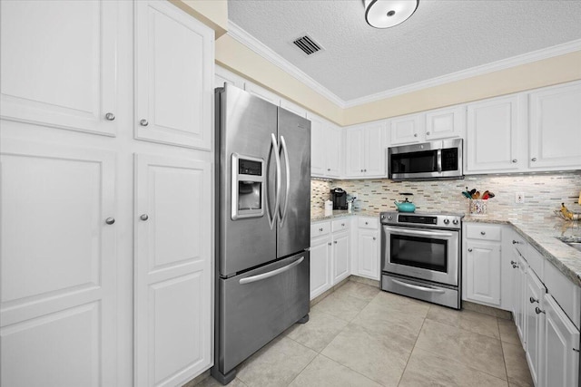 kitchen with white cabinets, backsplash, light tile patterned floors, and appliances with stainless steel finishes