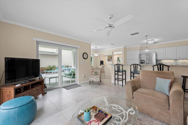 tiled living room with ceiling fan, a textured ceiling, and crown molding