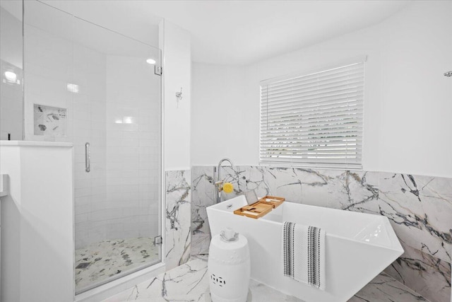 bathroom featuring shower with separate bathtub and tile walls