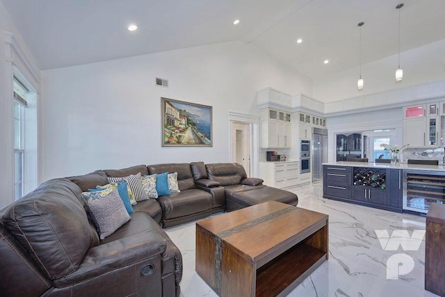 living room featuring bar, beverage cooler, and high vaulted ceiling