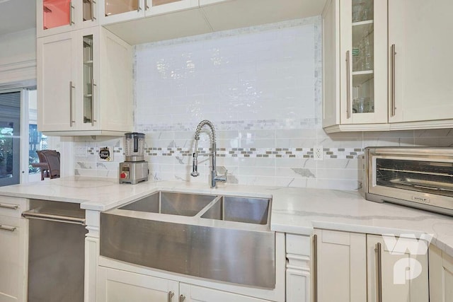 kitchen featuring white cabinetry, sink, decorative backsplash, and light stone countertops