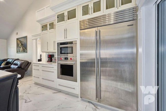 kitchen with white cabinetry, vaulted ceiling, and stainless steel appliances