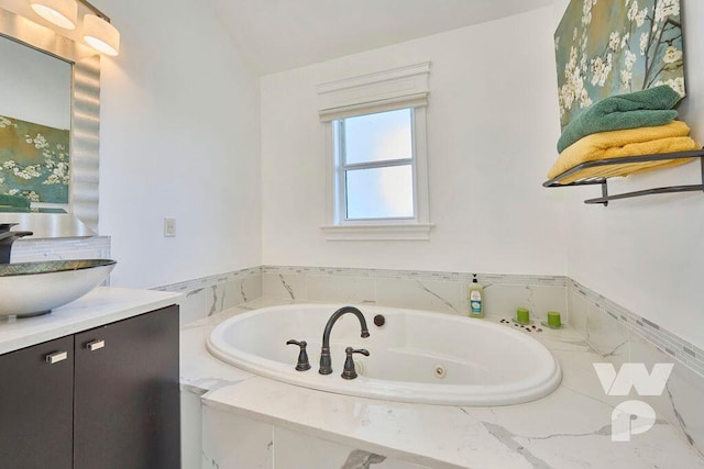 bathroom with vanity, a relaxing tiled tub, and lofted ceiling