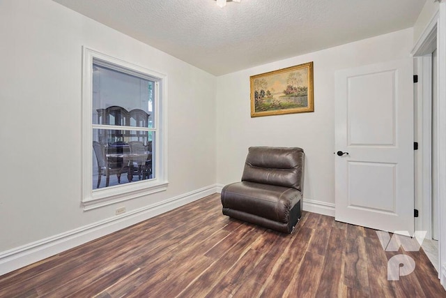 sitting room with dark wood-type flooring and a textured ceiling