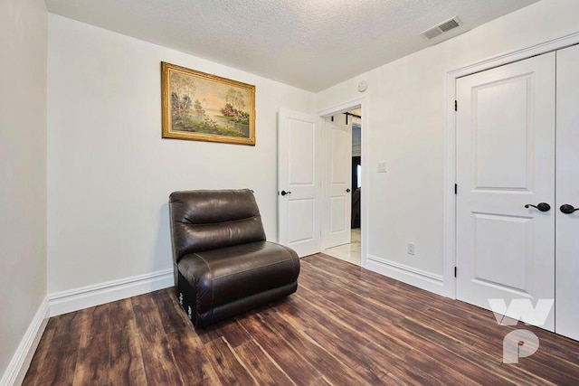 living area with dark wood-type flooring and a textured ceiling