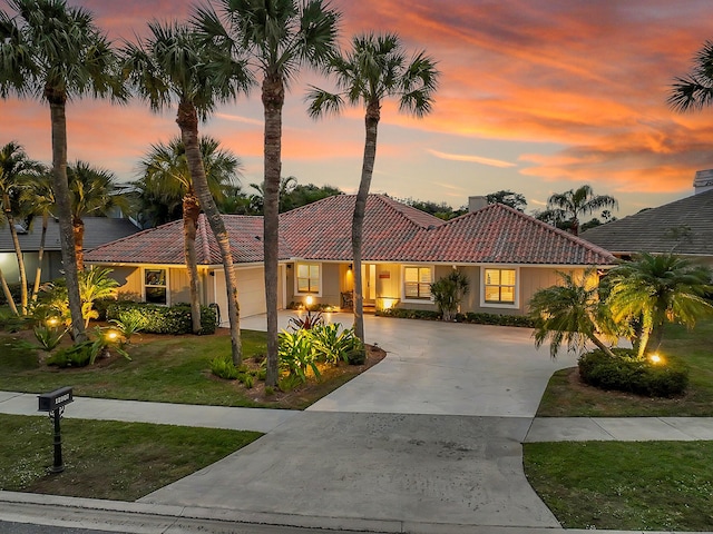 mediterranean / spanish-style home with a garage and a yard