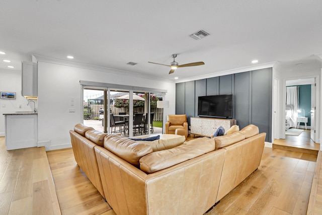 living room with sink, light hardwood / wood-style flooring, ornamental molding, and ceiling fan