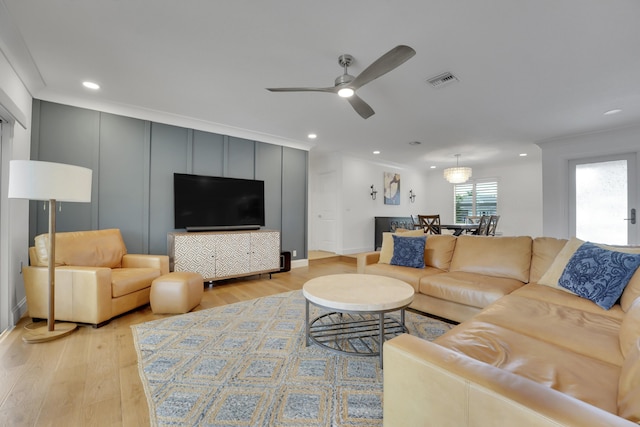 living room featuring ceiling fan, ornamental molding, and light hardwood / wood-style floors