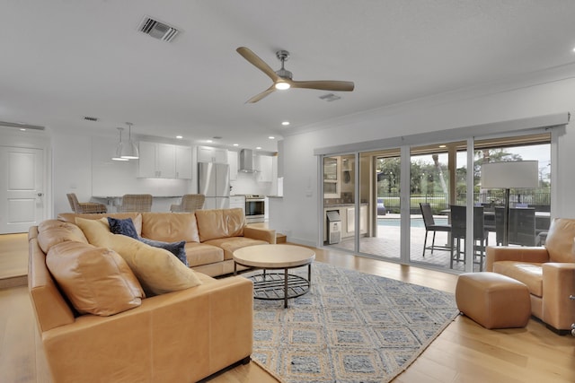 living room with crown molding, ceiling fan, and light hardwood / wood-style flooring