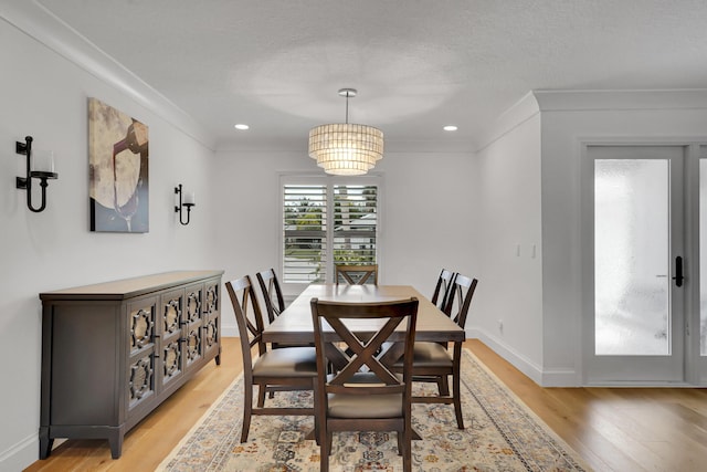 dining room with a notable chandelier, crown molding, light hardwood / wood-style floors, and a textured ceiling